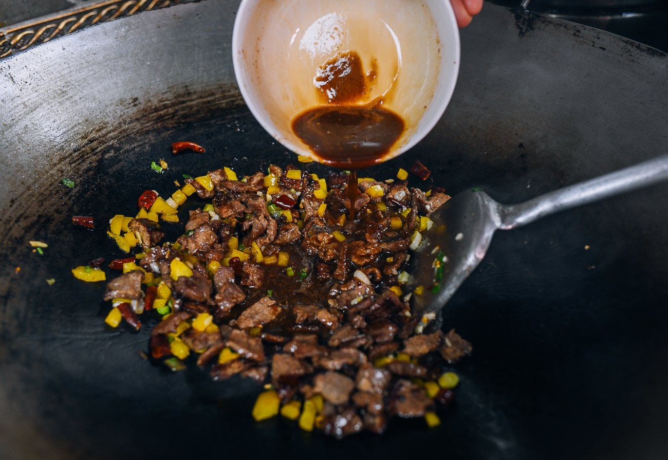 adding sauce to kung pao beef stir-fry