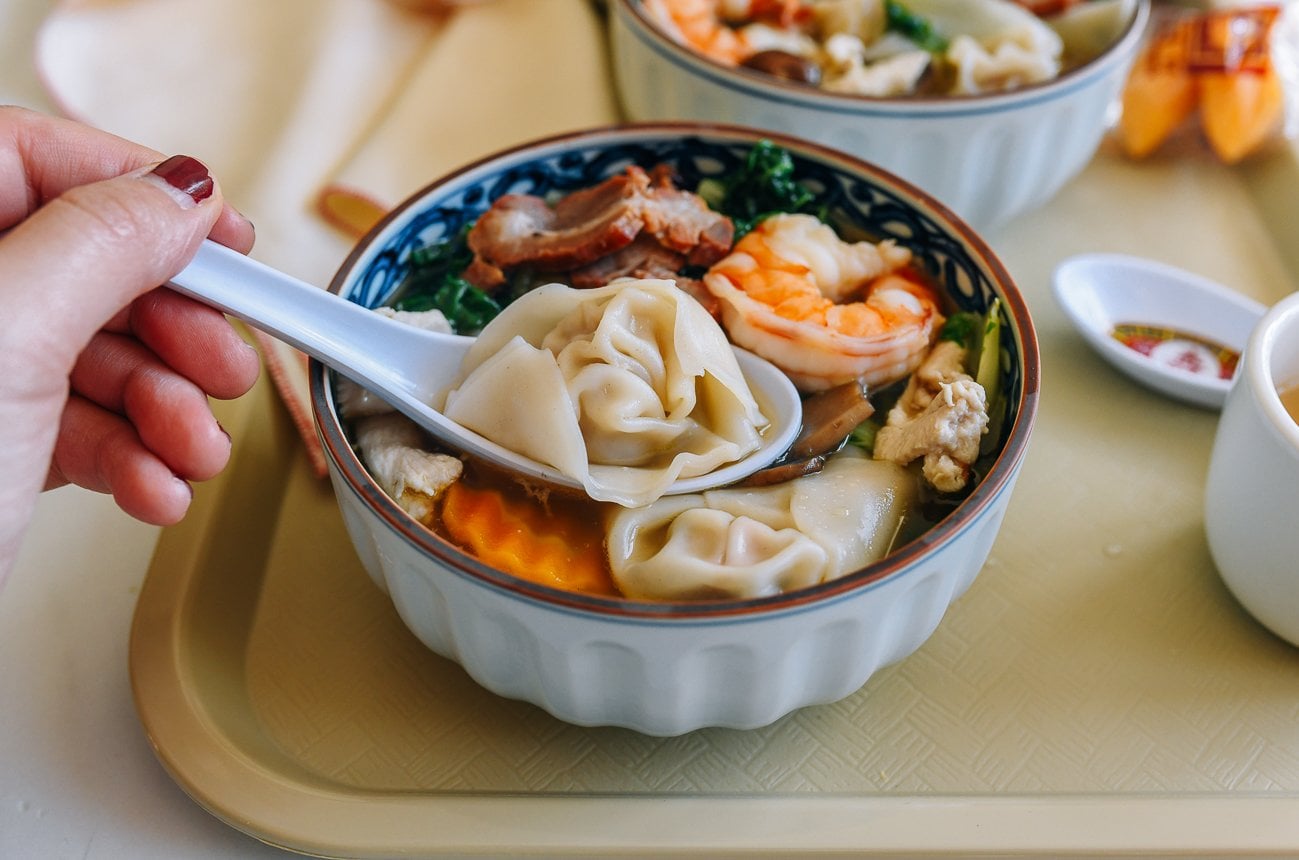 picking up a wonton in a bowl of wor wonton soup