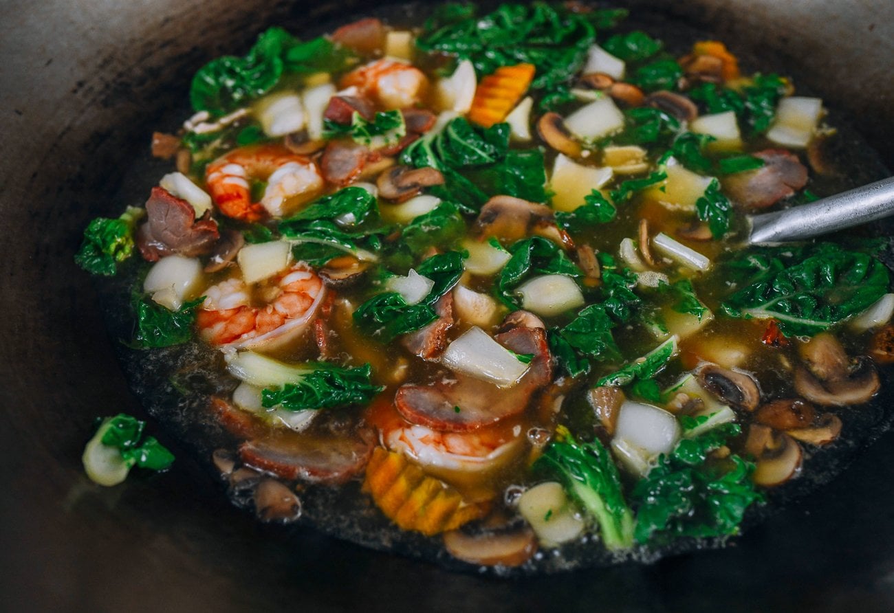 wok filled with soup with shrimp and chicken and vegetables