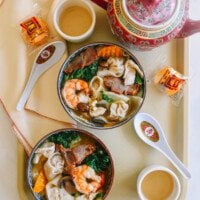 Bowls of Wor Wonton Soup on a tray with fortune cookies and tea