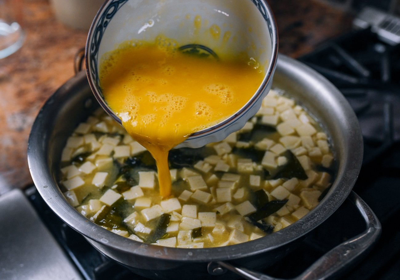 pouring egg into pot of miso soup