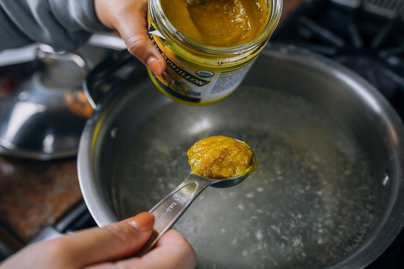 adding chicken bouillon paste to pot