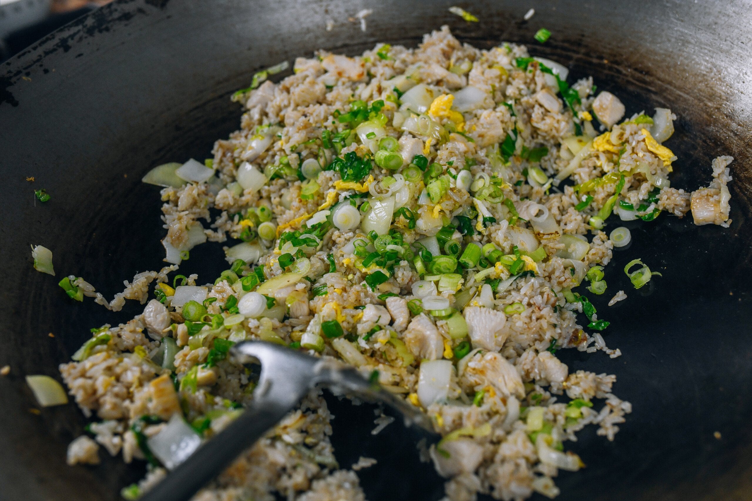 adding scallions to fried rice