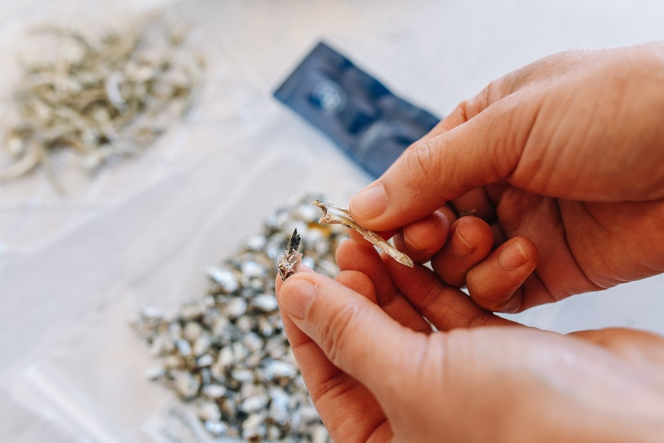 Removing head and guts from dried anchovy