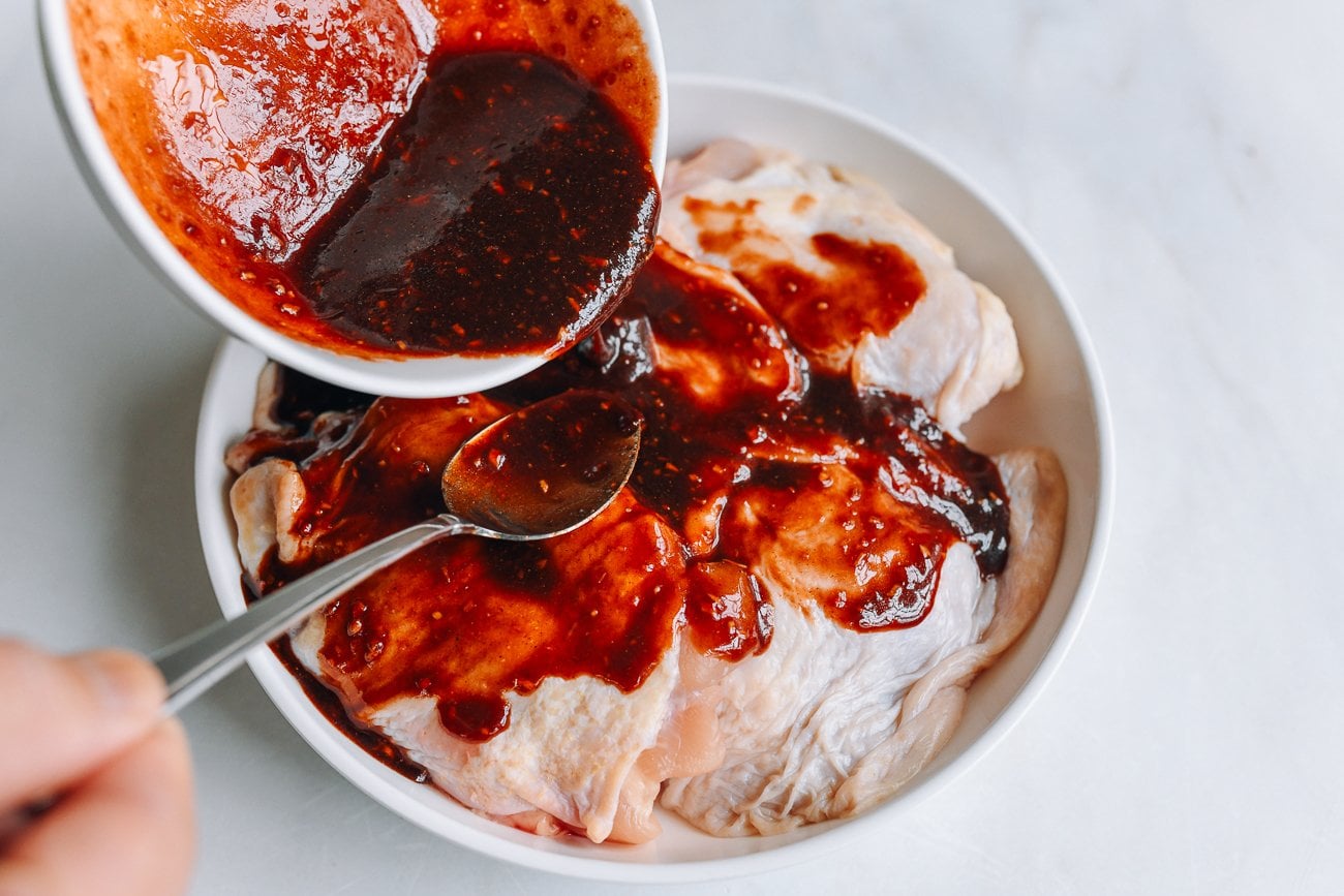 pouring char siu marinade over chicken thighs