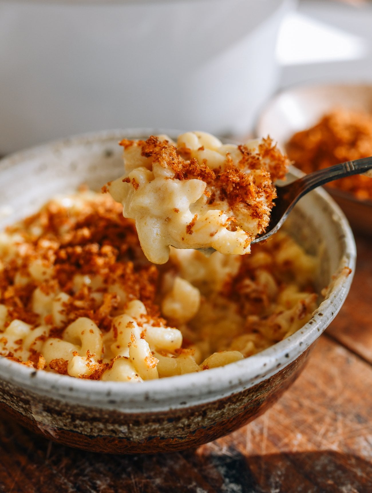 Picking up spoonful of mac and cheese with breadcrumb topping