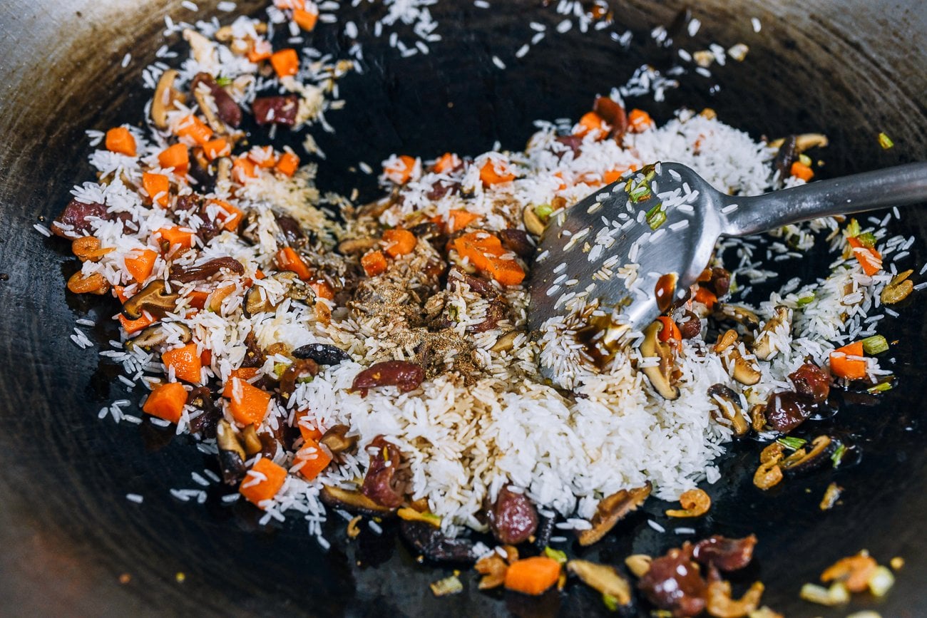 raw rice in wok with vegetables and chinese sasuage
