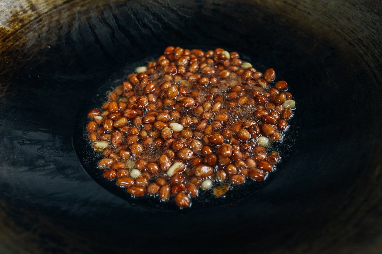 frying peanuts in oil in wok