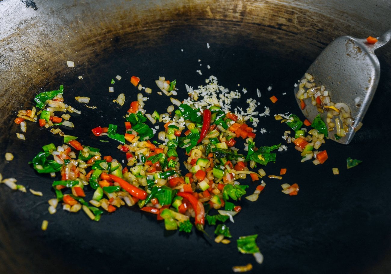 adding chopped garlic to vegetables in wok