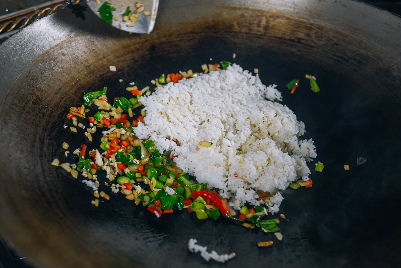 adding cooked rice to wok with vegetables