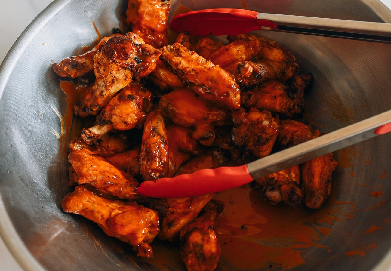 tossing air fryer buffalo wings in hot sauce