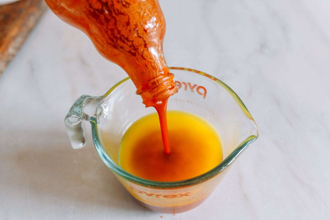 pouring hot sauce into measuring cup of melted butter