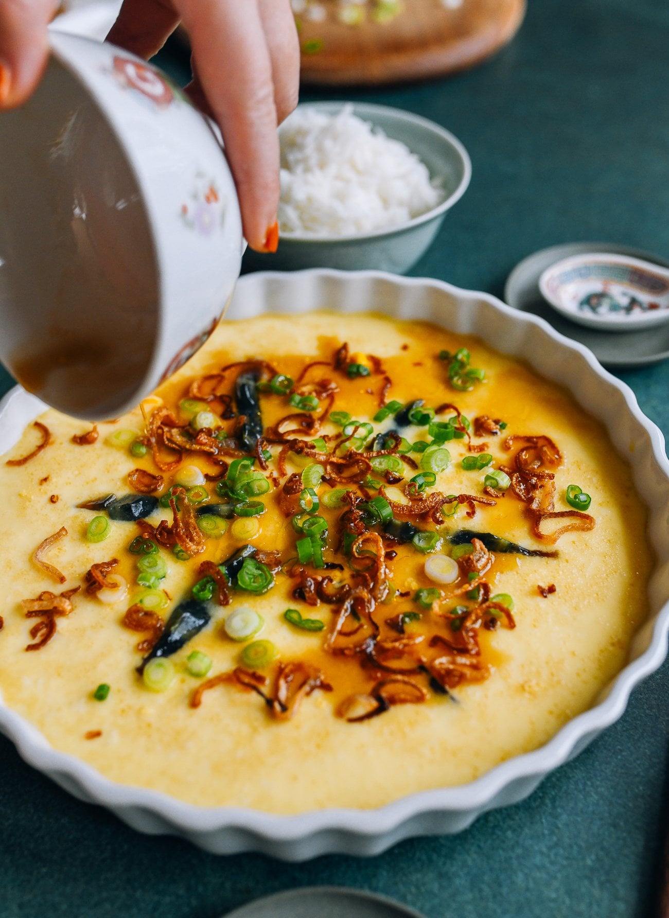 pouring sauce over steamed eggs