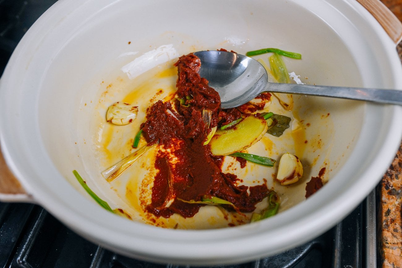 tomato paste, ginger, scallion, and bay leaf in pot