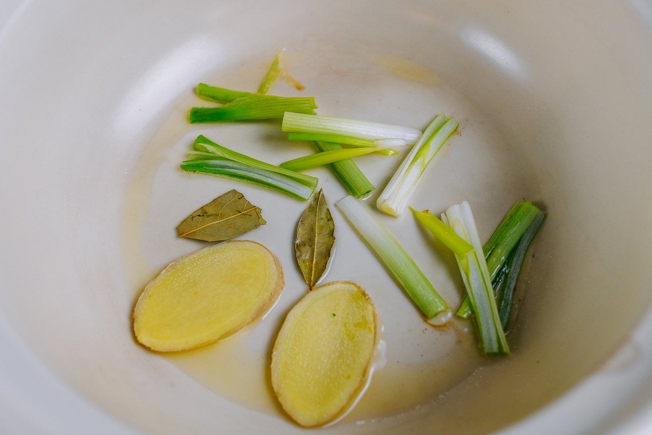 ginger, bay leaves, and scallions in pot