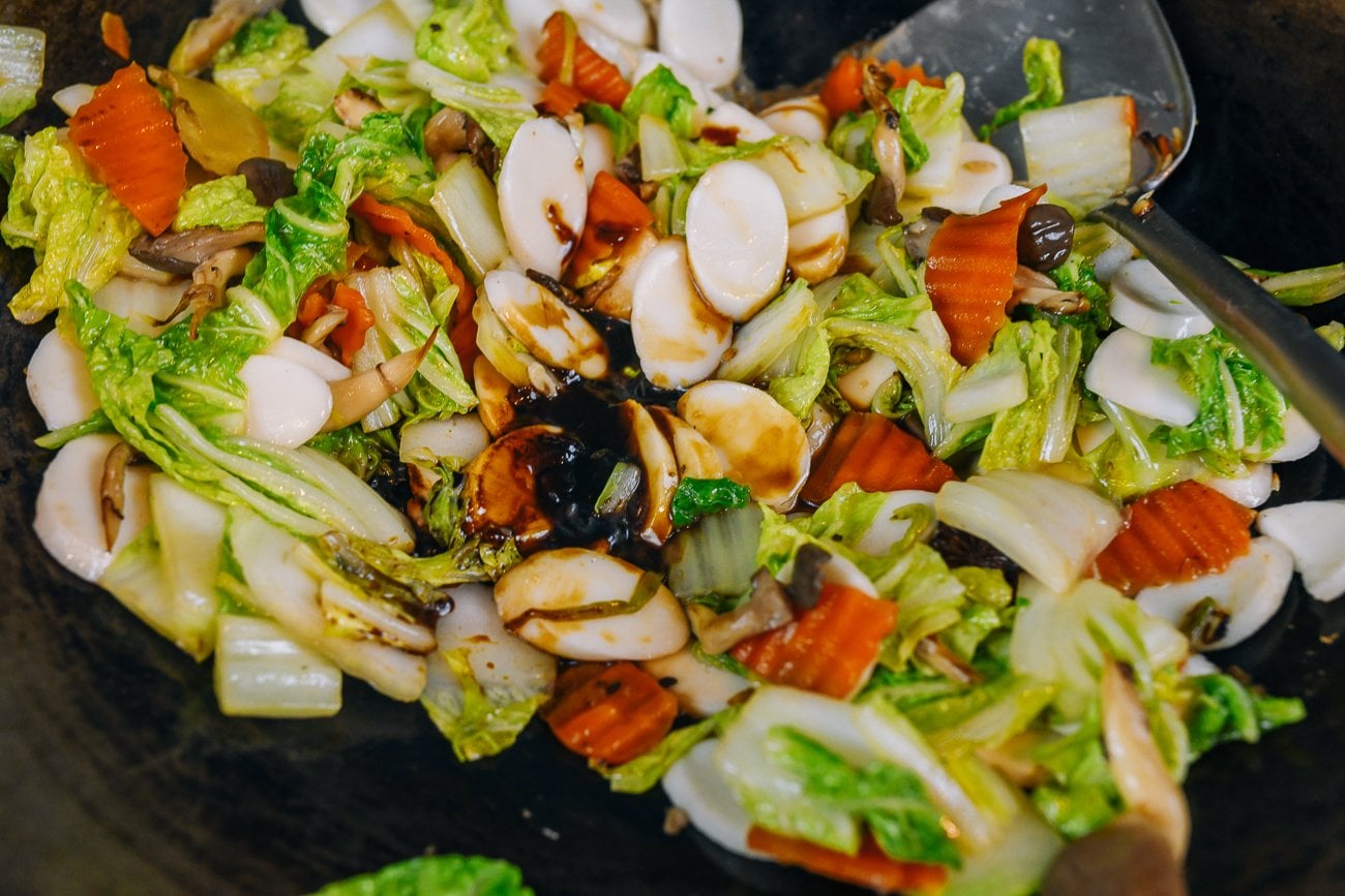 adding oyster sauce to rice cakes and vegetables