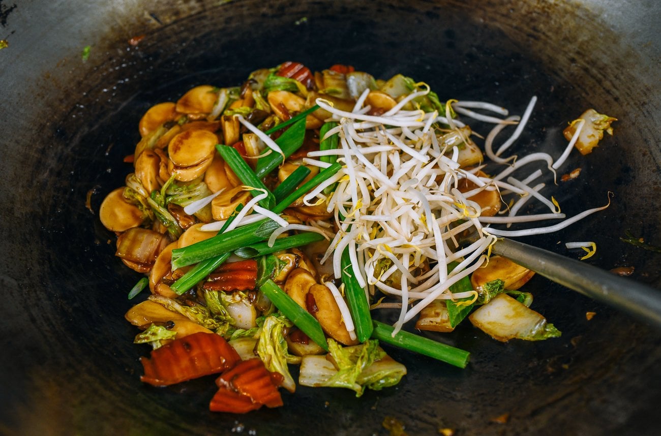 adding scallions and bean sprouts to rice cakes