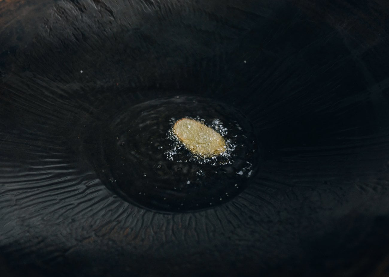 slice of ginger in oil in wok