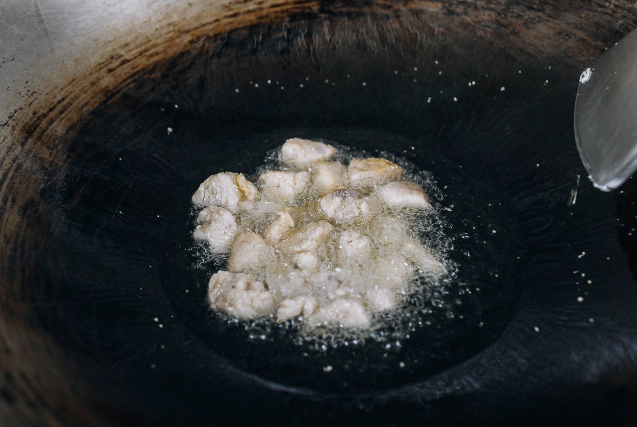dredged chicken pieces shallow-frying in wok