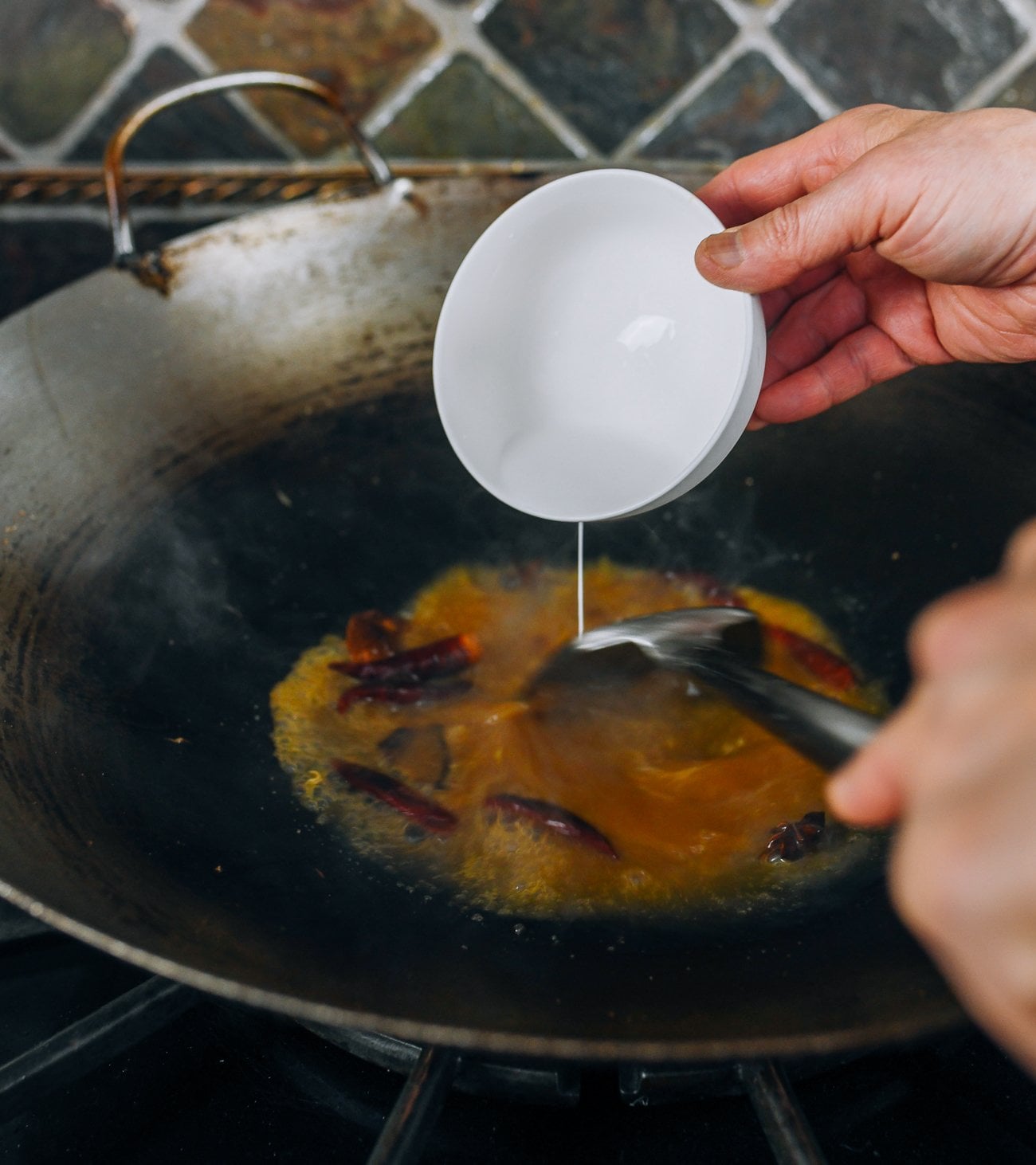 adding cornstarch slurry to sauce in wok