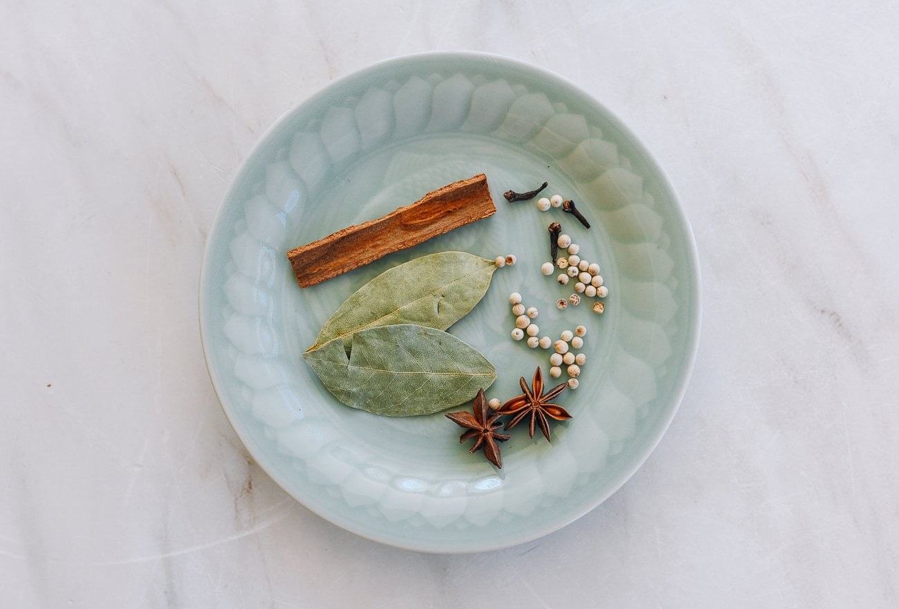 braising spices on plate - cinnamon, cloves, white peppercorns, bay leaves, star anise