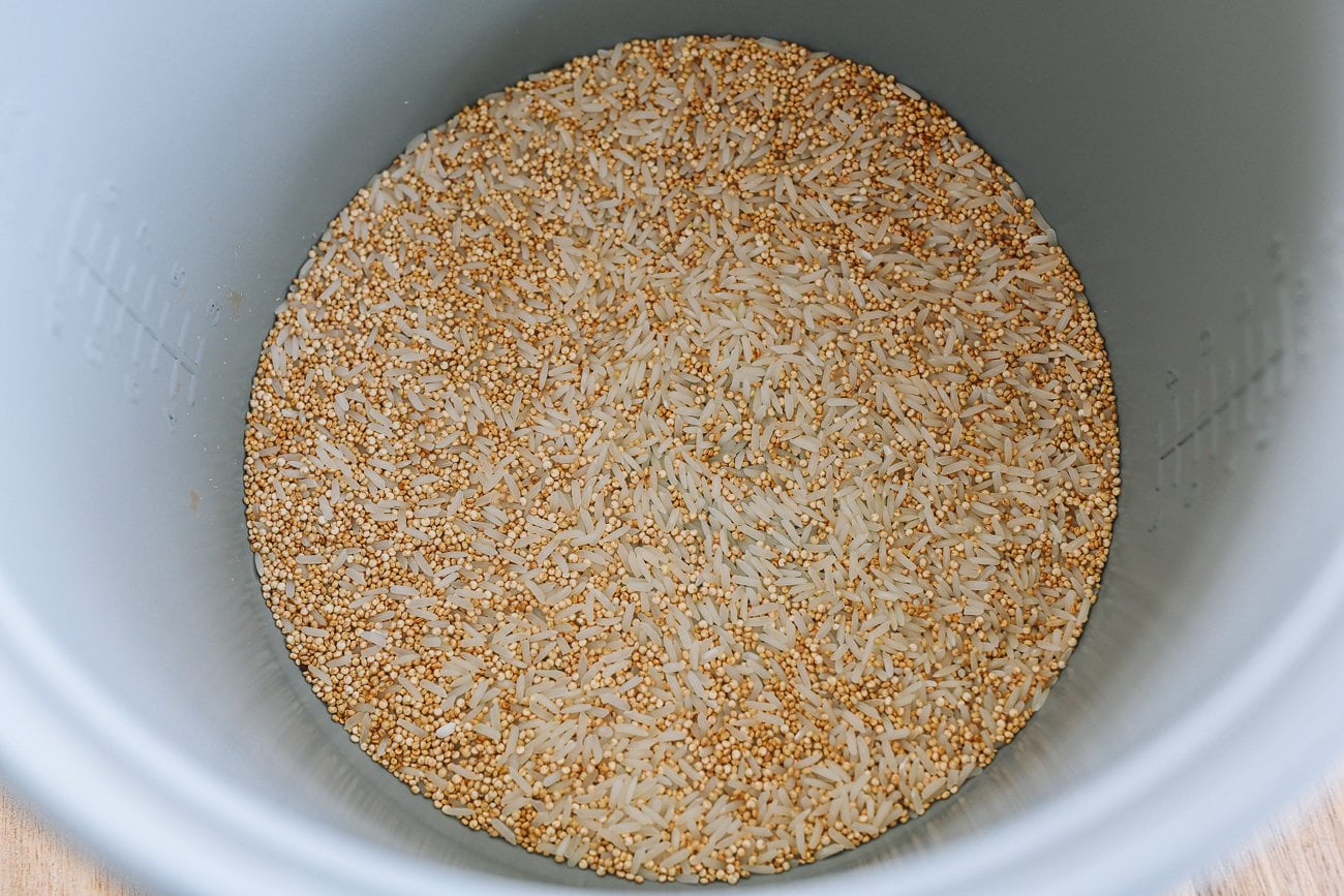 uncooked quinoa and rice in a rice cooker bowl