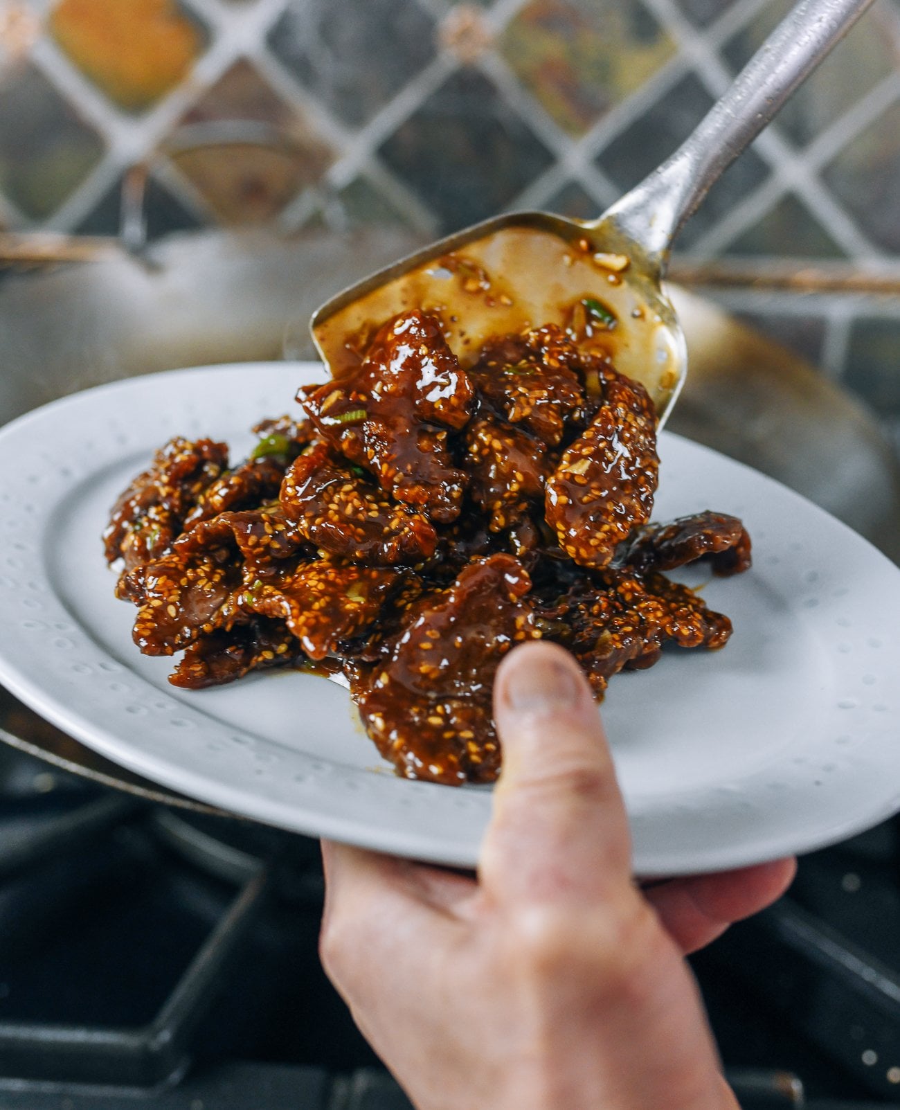 scooping sesame beef onto serving plate