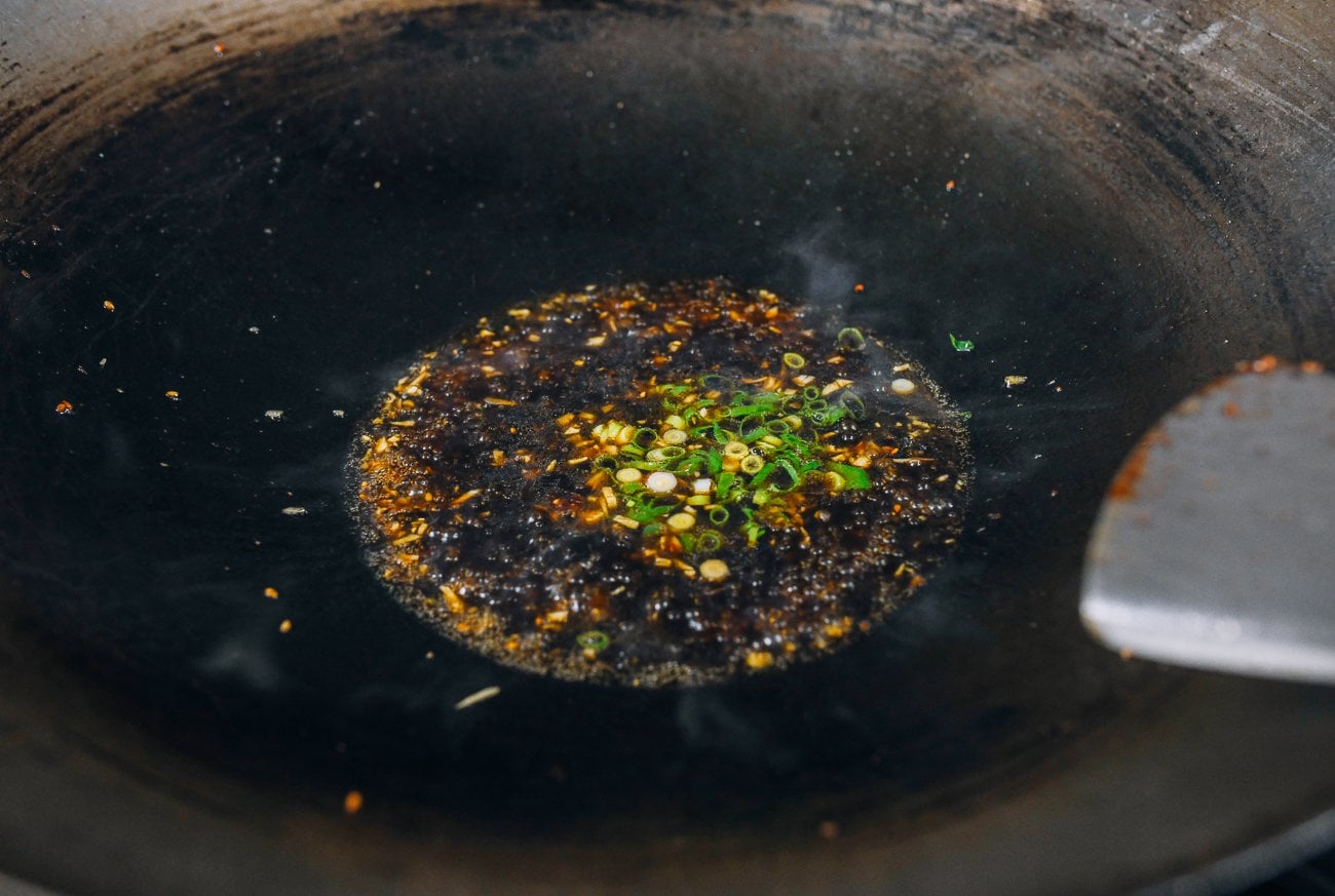 adding scallions to wok