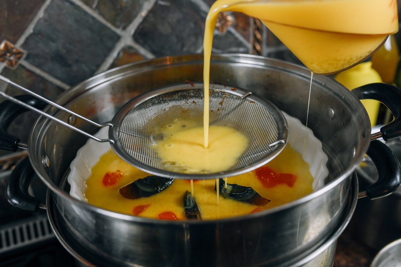 pouring egg mixture through strainer into dish