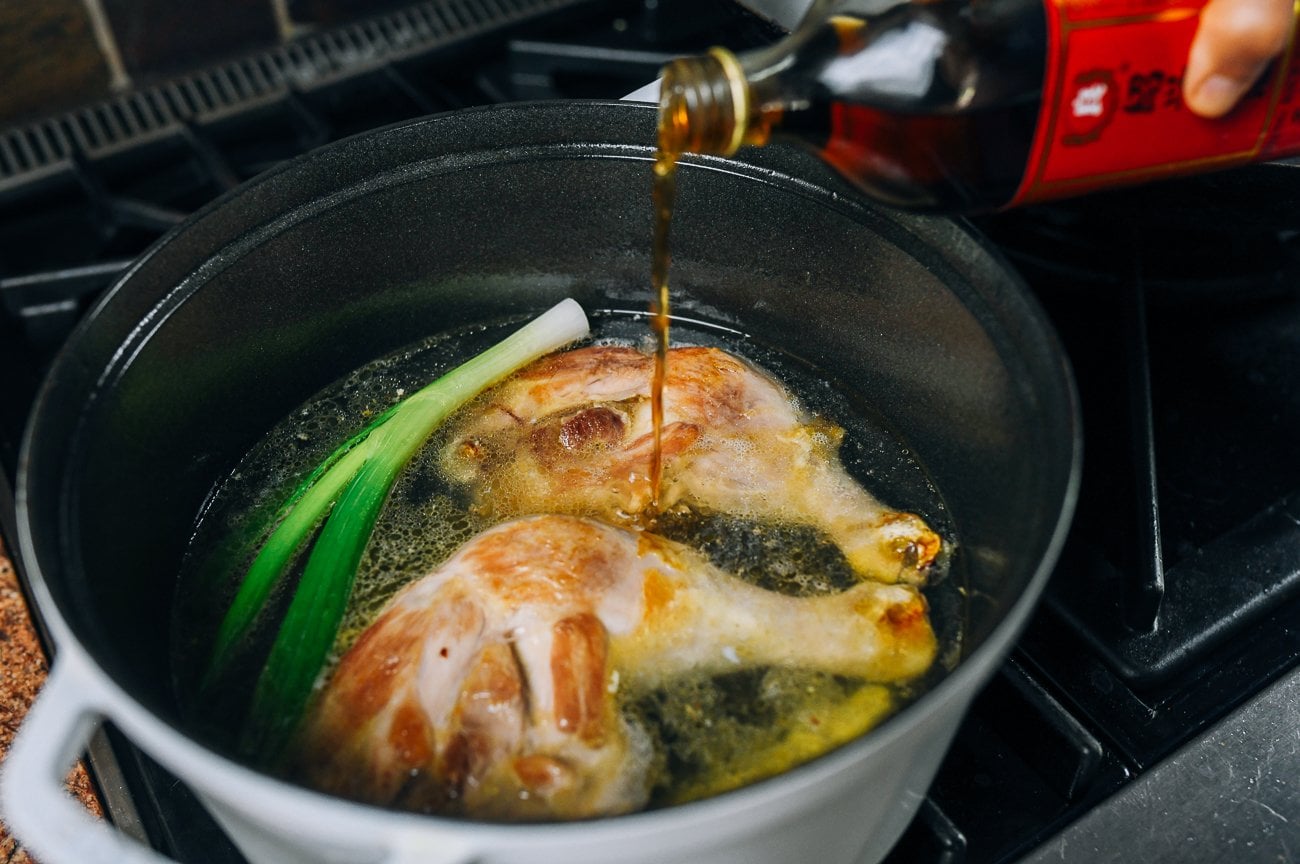 adding shaoxing wine to Chinese chicken noodle soup ingredients in pot