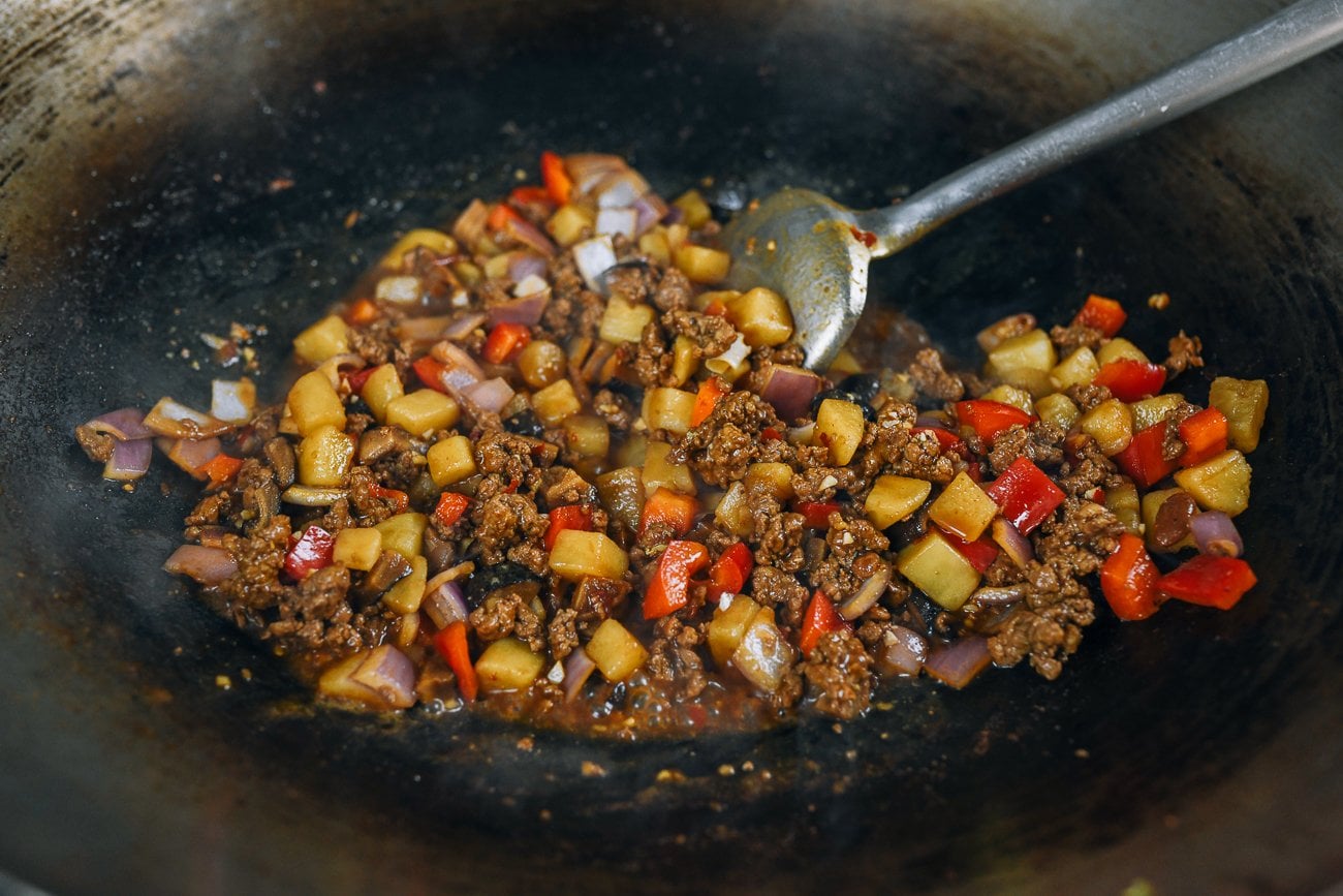 wok spatula stirring braised ground pork and potato in wok