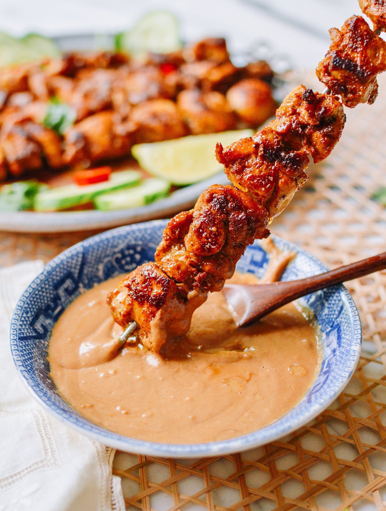 dipping chicken satay skewer into peanut sauce