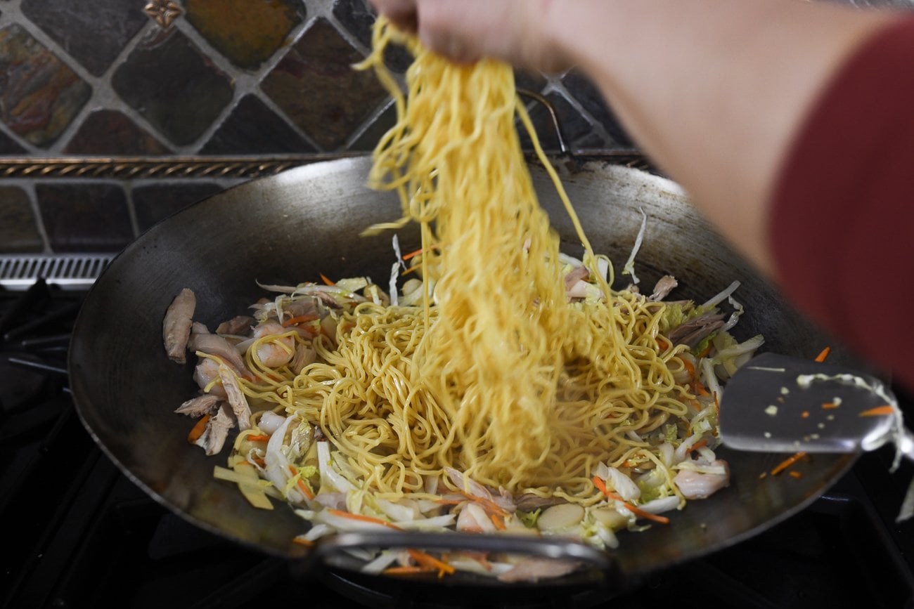 adding lo mein noodles to wok