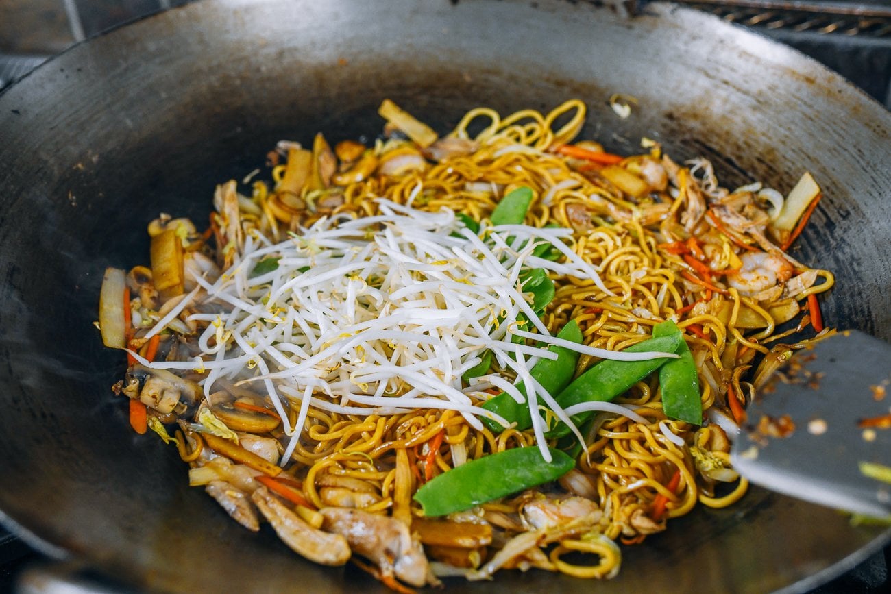Bean sprouts and snow peas added to lo mein in wok