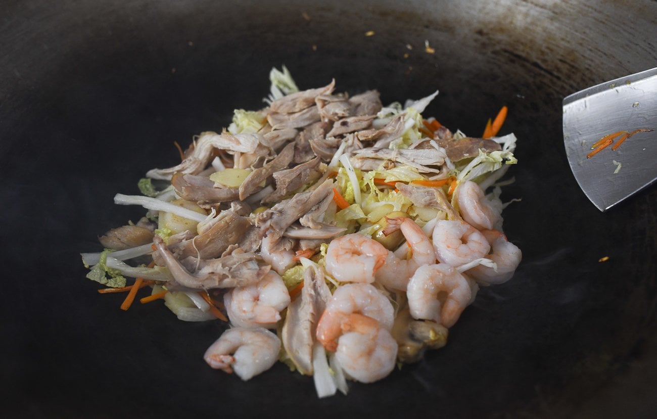 cooked chicken and shrimp added to vegetables in wok