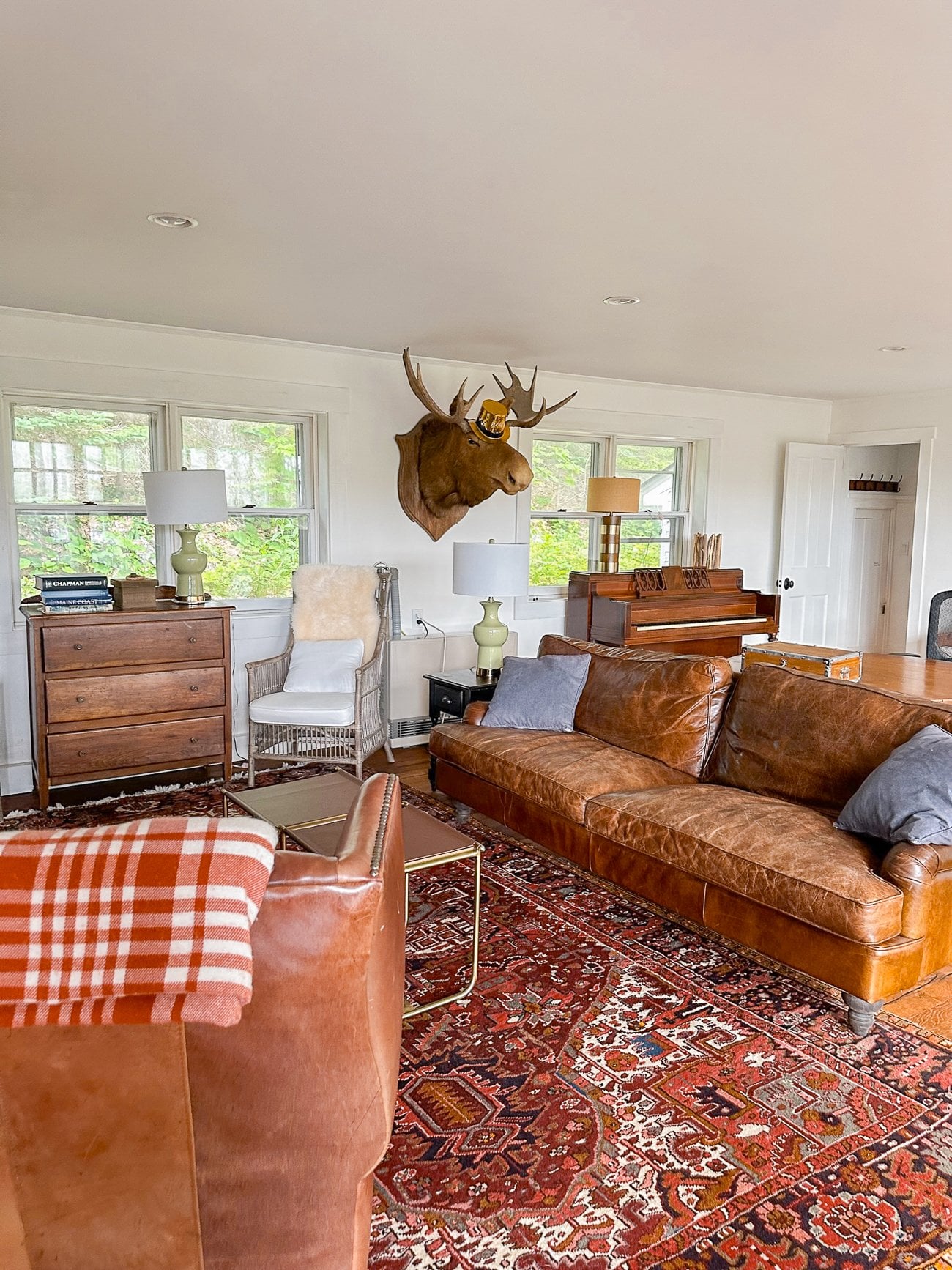 Living room with leather couch and armchair and a moose head on the wall wearing a New Year's Eve gold party hat