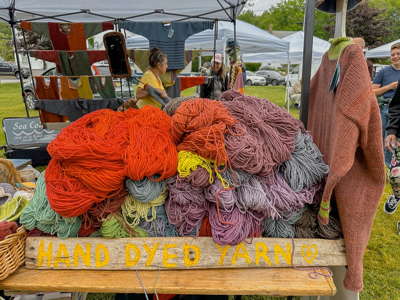 a wooden tray of hand-dyed yarn in reds, purples, blues, and greens at the Boothbay Harbor farmer's market