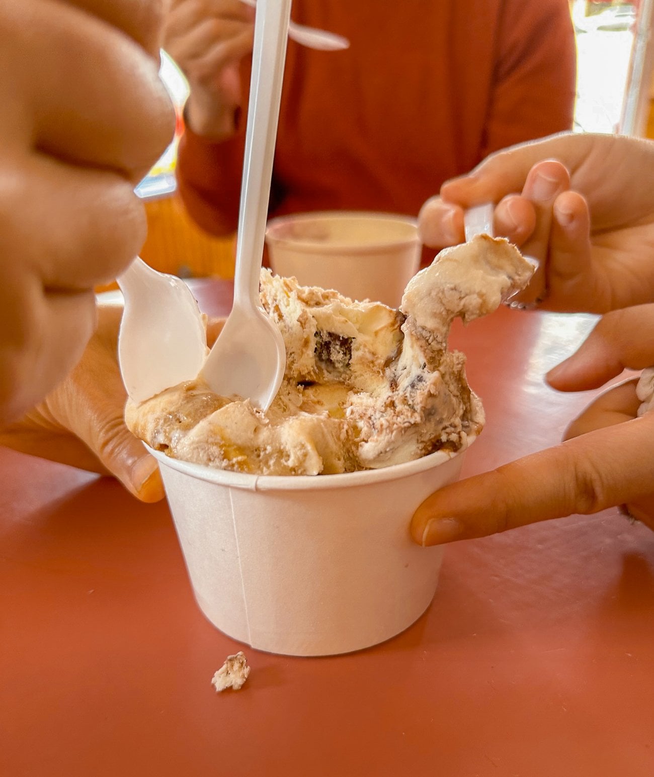 Multiple spoons digging into ice cream