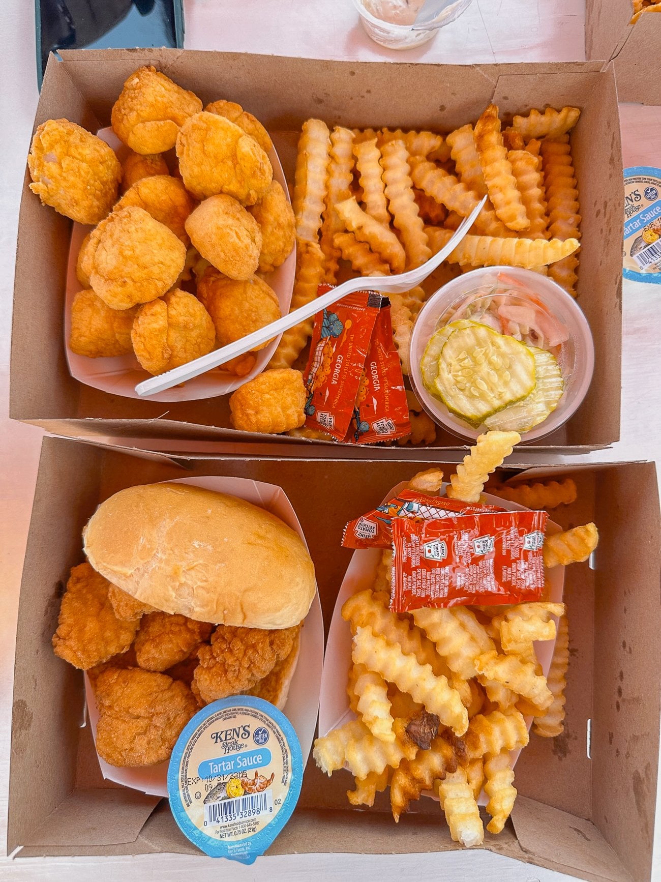 Fried scallops with french fries and a side of pickles and a fried fish sandwich with fries from The Clam Shack in Kennbunkport