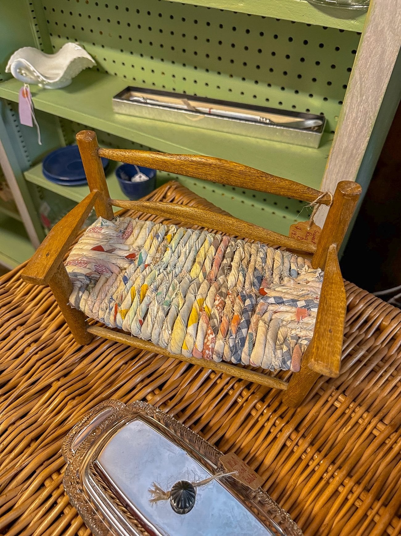 A small wooden doll bench with a multicolor woven seat