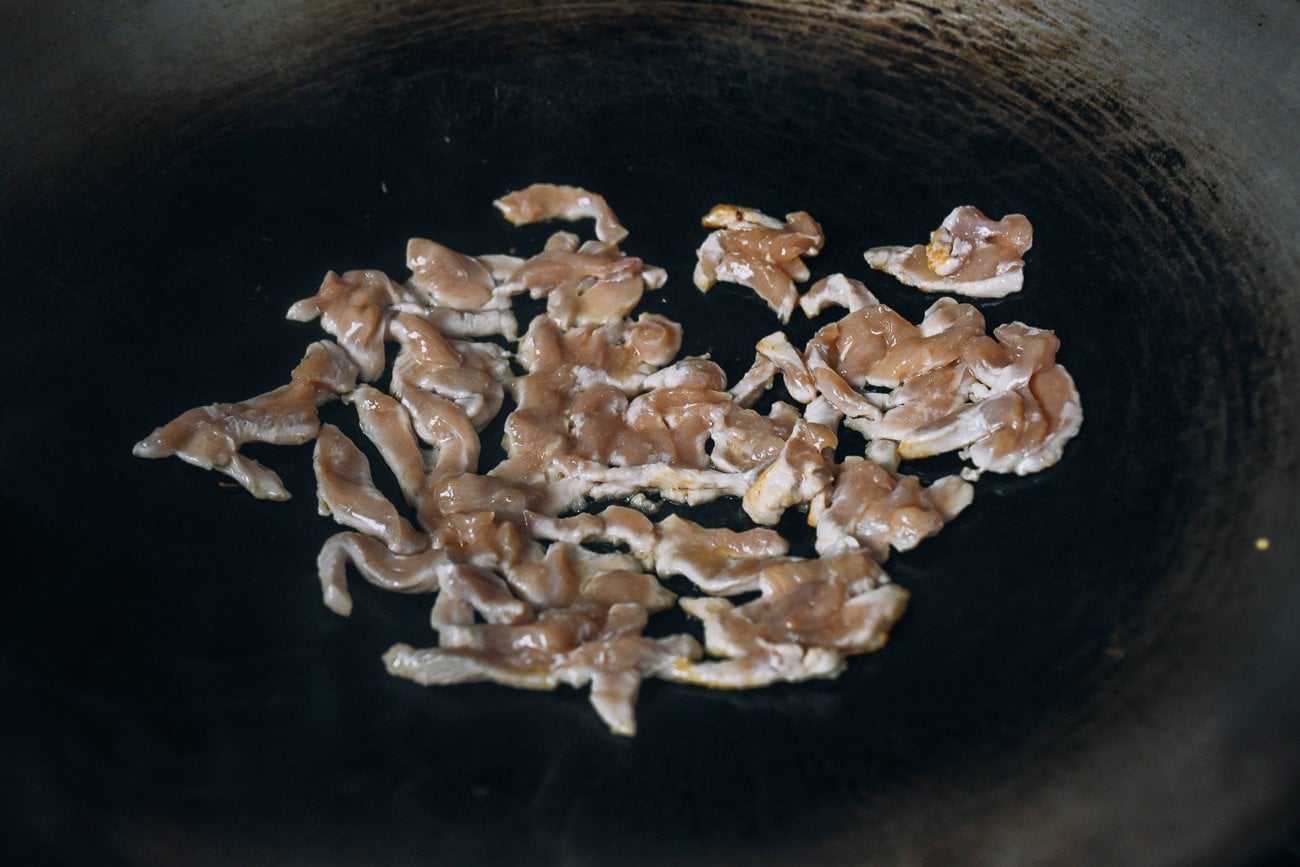 searing chicken pieces in wok
