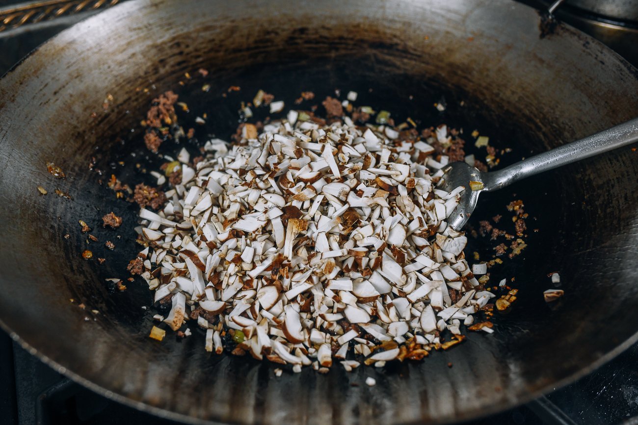 adding mushrooms to wok