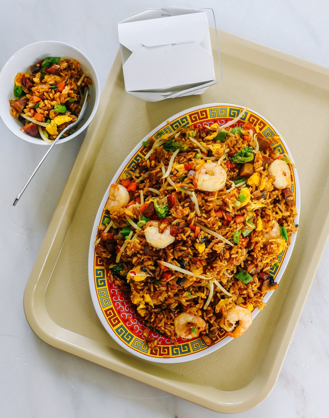plate of fried rice on tray with small bowl of fried rice next to it