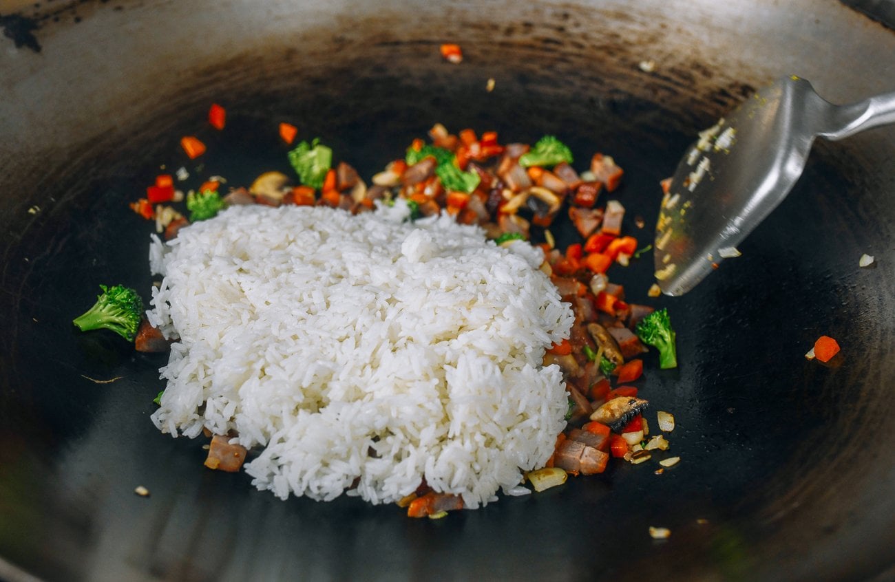 adding rice to wok with vegetables