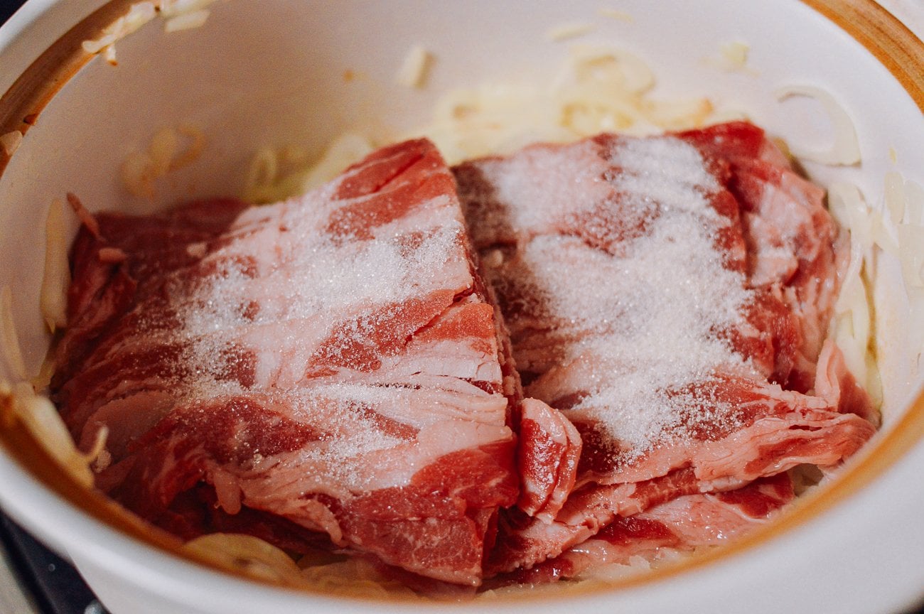 thin fatty beef, sugar, and onions in pot