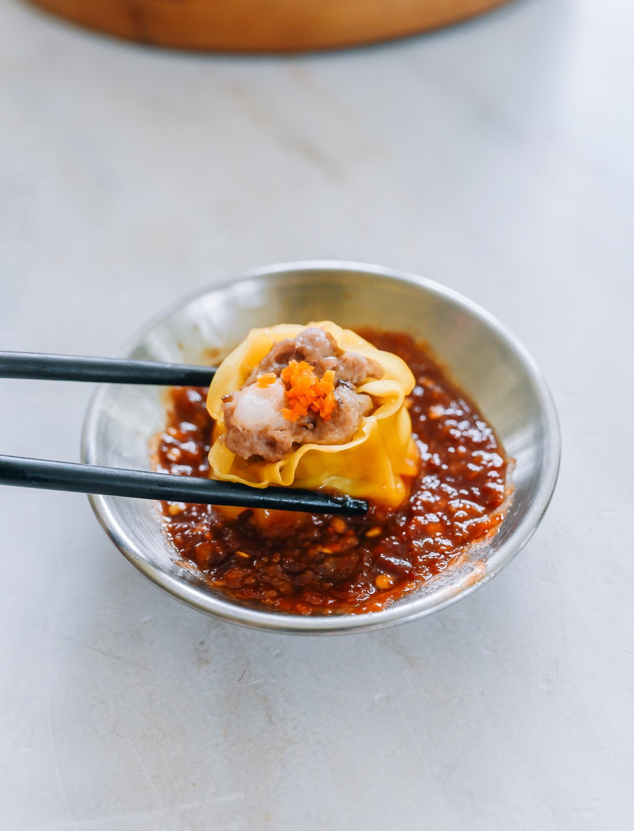 dipping siu mai into chili garlic sauce