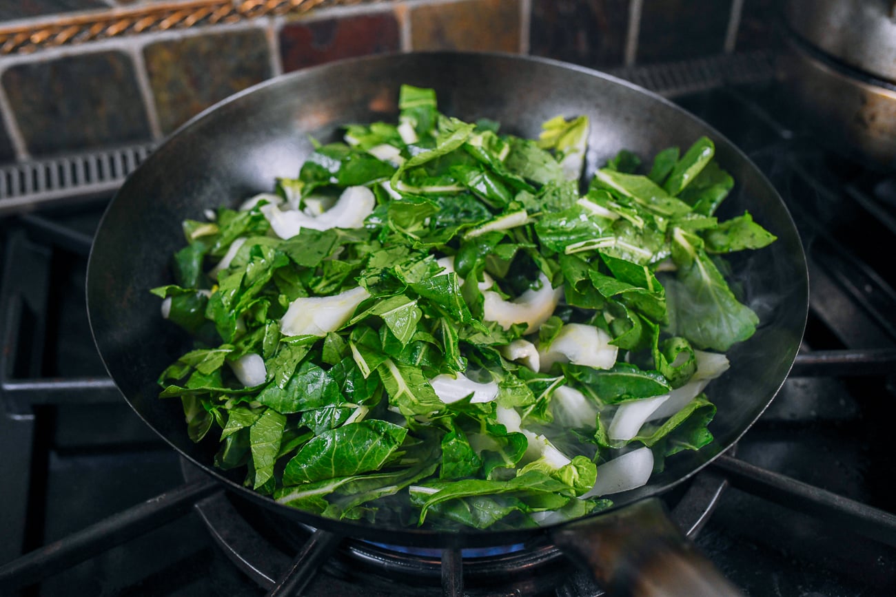 stir-frying sliced bok choy in wok