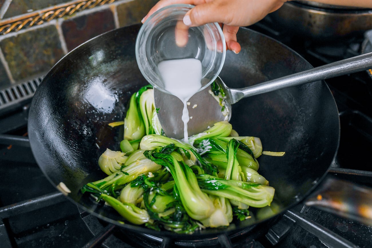 adding cornstarch slurry to bok choy stir-fry
