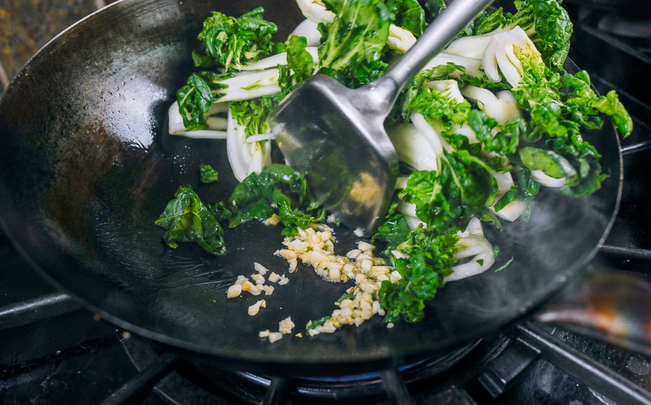 adding garlic to bok choy stir-fry