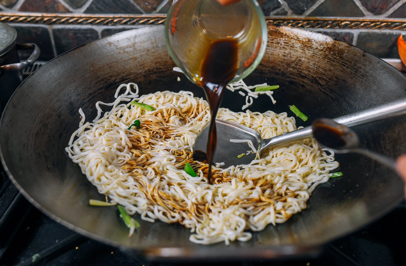 drizzling sauce over e-fu noodles